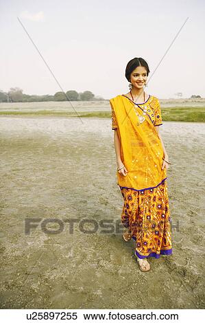 Stock Photography - Young woman walking on the riverbank and smiling, Agra, Uttar Pradesh, India. Fotosearch