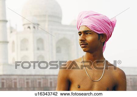 Stock Image - Close-up of a young man in front of a mausoleum, Taj Mahal, Agra, Uttar Pradesh, India. Fotosearch