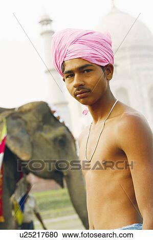 Stock Image - Close-up of a young man standing in front of an elephant, Taj Mahal, Agra, Uttar Pradesh, India. Fotosearch