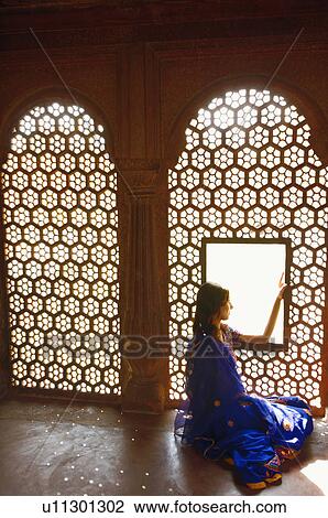 Stock Image - Side profile of a young woman sitting on the floor of a mausoleum, Taj Mahal, Agra, Uttar Pradesh, India. Fotosearch