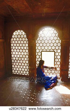 Stock Image - Side profile of a young woman sitting on the floor of a mausoleum, Taj Mahal, Agra, Uttar Pradesh, India. Fotosearch