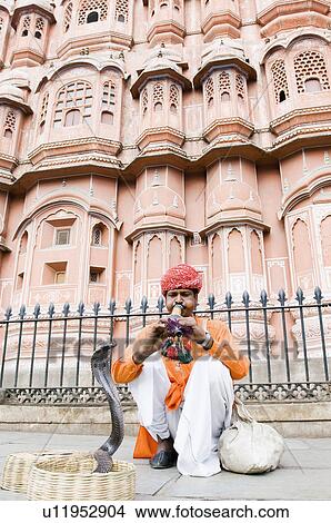 Picture - Snake charmer playing a flute in front of a palace, Hawa Mahal, Jaipur, Rajasthan, India. Fotosearch