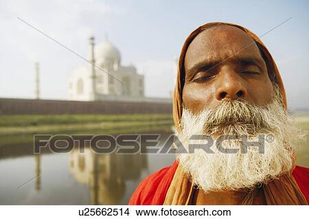 Picture - Close-up of a priest meditating on the riverbank with his eyes closed, Taj Mahal, Agra, Uttar Pradesh, India. Fotosearch