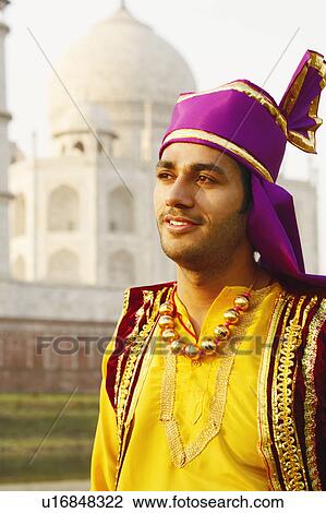 Stock Image - Close-up of a young man in front of a mausoleum, Taj Mahal, Agra, Uttar Pradesh, India. Fotosearch