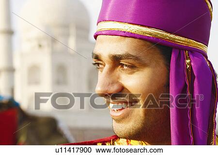Stock Image - Close-up of a young man smiling in front of a mausoleum, Taj Mahal, Agra, Uttar Pradesh, India. Fotosearch