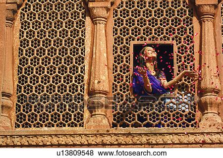 Low angle view of a young woman throwing rose petal from a window View Large Photo Image Stock Photo - Low angle view of a young woman throwing rose petal from a window. Fotosearch