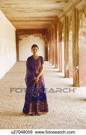 Stock Photo - Portrait of a young woman standing and smiling, Agra Fort, Agra, Uttar Pradesh, India. Fotosearch