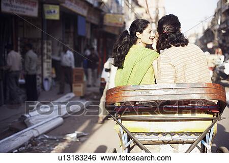 Stock Photograph - Rear view of a young couple sitting in a rickshaw. Fotosearch