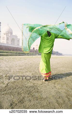 Stock Photography - Rear view of a young woman holding her stole on the riverbank, Taj Mahal, Agra, Uttar Pradesh, India. Fotosearch