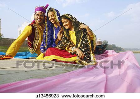 Stock Image - Two young women and a young man sitting in a boat. Fotosearch