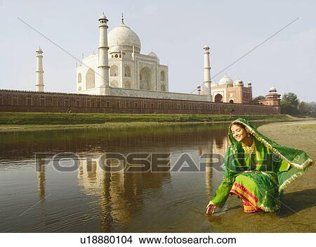 Young woman crouching on the riverbank, Taj Mahal, Agra, Uttar Pradesh, India View Large Photo Image Picture - Young woman crouching on the riverbank, Taj Mahal, Agra, Uttar Pradesh, India. Fotosearch