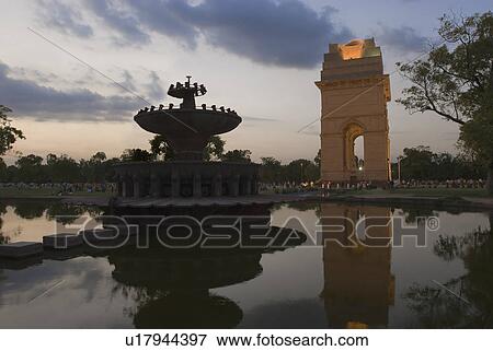 Stock Photo - Reflection of a stone gateway in water at dusk, India Gate, New Delhi, India. Fotosearch