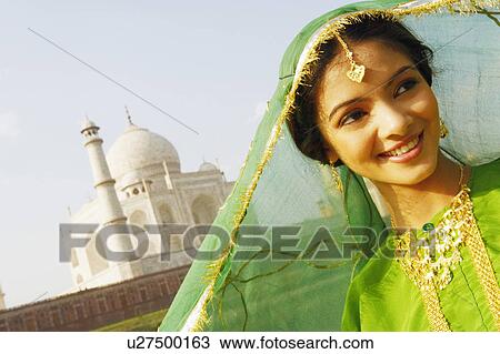 Stock Image - Close-up of a young woman smiling, Taj Mahal, Agra, Uttar Pradesh, India. Fotosearch