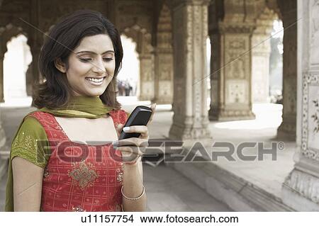 Picture - Close-up of a young woman using a mobile phone. Fotosearch