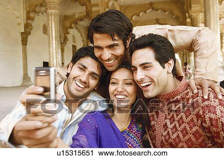 Close-up of three young men and a young woman looking at a mobile phone and smiling, Agra, Uttar Pradesh, India View Large Photo Image Stock Image - Close-up of three young men and a young woman looking at a mobile phone and smiling, Agra, Uttar Pradesh, India. Fotosearch
