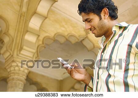 Low angle view of a young man operating a mobile phone View Large Photo Image Stock Image - Low angle view of a young man operating a mobile phone. Fotosearch