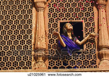 Low angle view of a young woman throwing rose petal from a window View Large Photo Image Stock Image - Low angle view of a young woman throwing rose petal from a window. Fotosearch