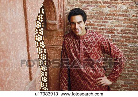 Stock Image - Portrait of a young man leaning against a wall and smiling. Fotosearch
