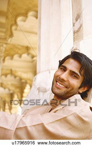 Portrait of a young man leaning against a wall and smiling View Large Photo Image Stock Photograph - Portrait of a young man leaning against a wall and smiling. Fotosearch