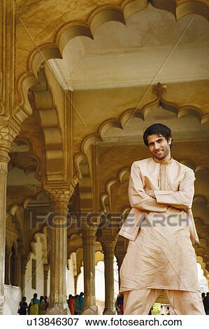 Stock Photo - Portrait of a young man standing with his arms folded and smiling, Agra Fort, Agra, Uttar Pradesh, India. Fotosearch