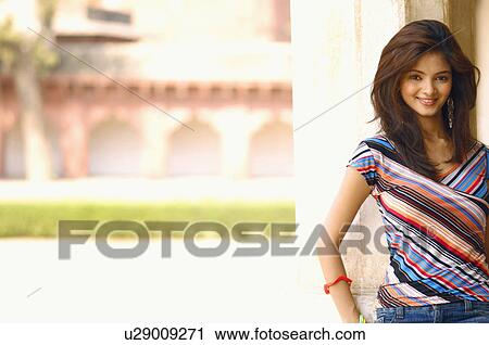 Stock Image - Portrait of a young woman leaning against a column and smiling. Fotosearch