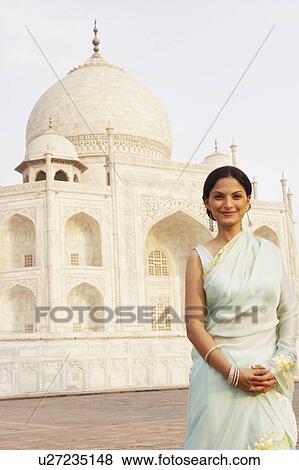 Stock Photo - Portrait of a young woman standing in front of a mausoleum, Taj Mahal, Agra, Uttar Pradesh, India. Fotosearch