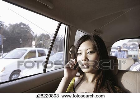 Portrait of a young woman talking on a mobile phone in a car View Large Photo Image Stock Image - Portrait of a young woman talking on a mobile phone in a car. Fotosearch