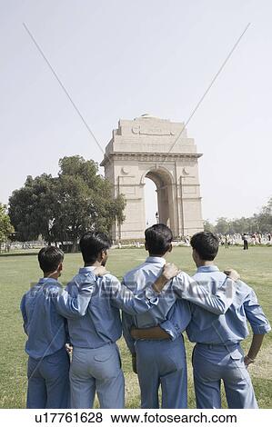 Stock Photo - Rear view of four boys standing with their arms around each other in front of a monument, India Gate, New Delhi, India. Fotosearch