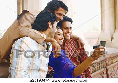 Picture - Side profile of a group of friends taking a photograph of themselves. Fotosearch