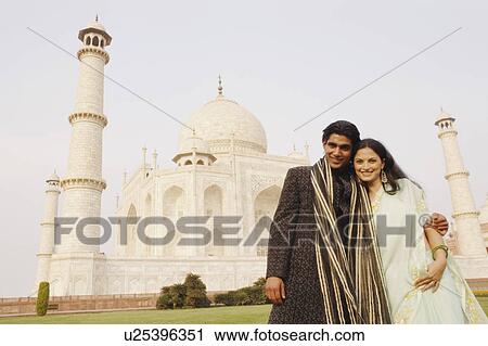 Stock Image - Young couple standing in front of a mausoleum, Taj Mahal, Agra, Uttar Pradesh, India. Fotosearch
