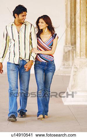Stock Image - Young couple walking side by side. Fotosearch