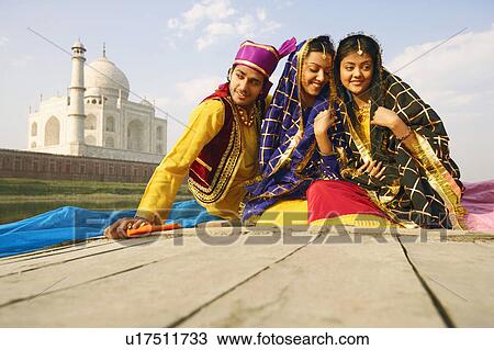 Stock Image - Young man and two young women sitting in a boat, Taj Mahal, Agra, Uttar Pradesh, India. Fotosearch