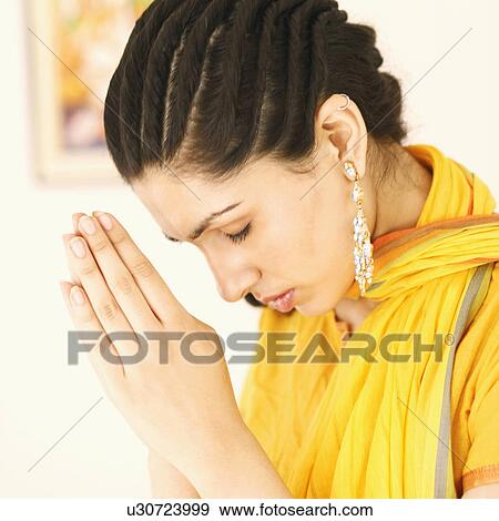 Stock Photo - Close-up of a young woman praying. Fotosearch