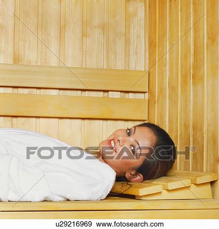 Stock Photo - Portrait of a young woman lying in a sauna. Fotosearch