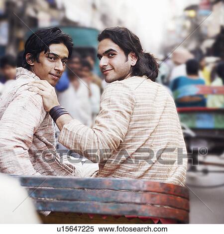 Stock Photography - Rear view of two young men sitting in a rickshaw. Fotosearch