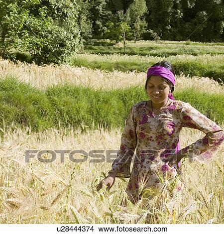 Picture - Teenage girl standing in a wheat field and smiling. Fotosearch