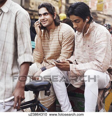 Stock Image - Two young men sitting in a rickshaw. Fotosearch