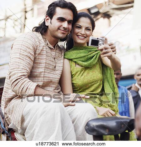Young couple sitting in a rickshaw and taking a photograph of themselves View Large Photo Image Stock Image - Young couple sitting in a rickshaw and taking a photograph of themselves. Fotosearch