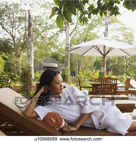 Stock Photo - Young woman lying on her side with her head in her hand. Fotosearch