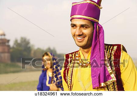 Stock Image - Close-up of a young man smiling with a young woman in the background. Fotosearch