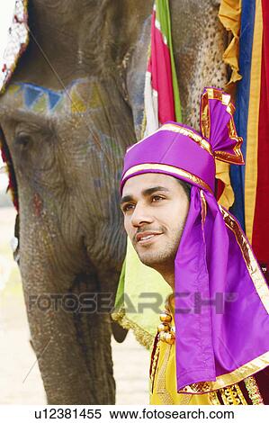 Close-up of a young man standing with an elephant View Large Photo Image Stock Photography - Close-up of a young man standing with an elephant. Fotosearch