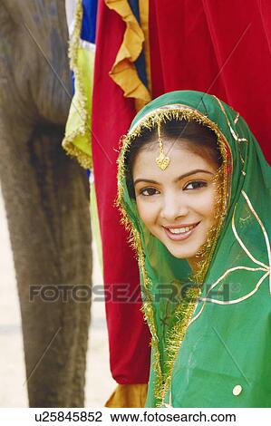 Portrait of a young woman standing with an elephant View Large Photo Image Stock Image - Portrait of a young woman standing with an elephant. Fotosearch