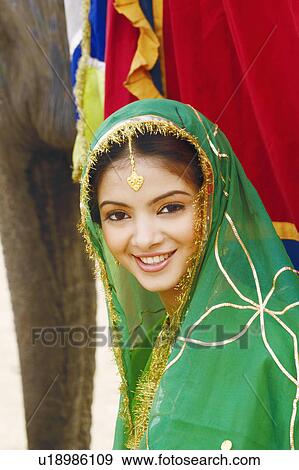 Portrait of a young woman standing with an elephant View Large Photo Image Stock Photo - Portrait of a young woman standing with an elephant. Fotosearch