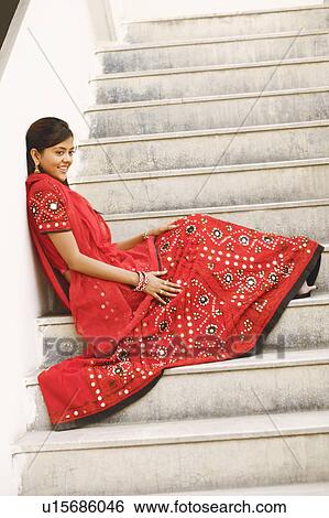 Stock Photograph - Side profile of a young woman sitting on the staircase and smiling. Fotosearch