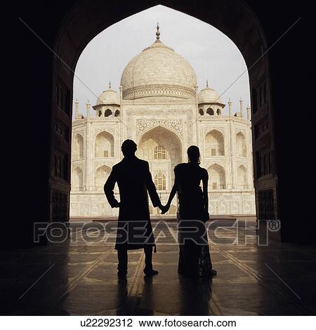 Stock Image - Silhouette of a couple standing in front of a mausoleum, Taj Mahal, Agra, Uttar Pradesh, India. Fotosearch