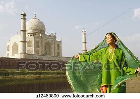 Stock Image - Young woman standing with her eyes closed on the riverbank, Taj Mahal, Agra, Uttar Pradesh, India. Fotosearch