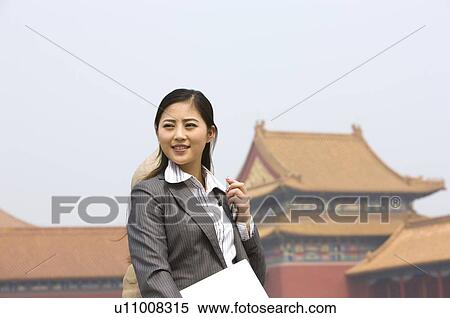 Stock Photography - Business woman holding her cell phone and laptop. Fotosearch