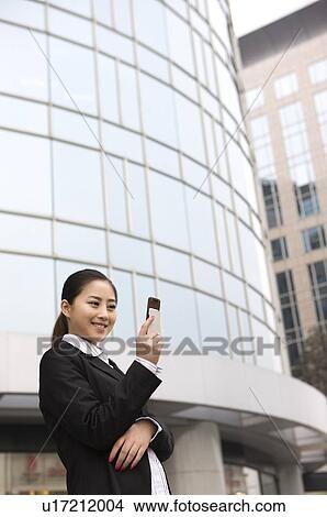 Picture - Business woman looking at her cell phone, smiling. Fotosearch