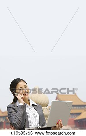 Business woman on the phone with laptop in her left hand View Large Photo Image Stock Image - Business woman on the phone with laptop in her left hand. Fotosearch