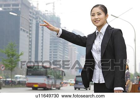 Stock Image - Business woman taking a taxi. Fotosearch